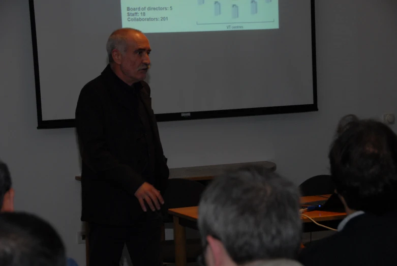 an old man presenting in front of a class