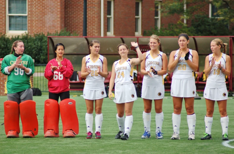 girls in soccer uniforms standing with their hands folded