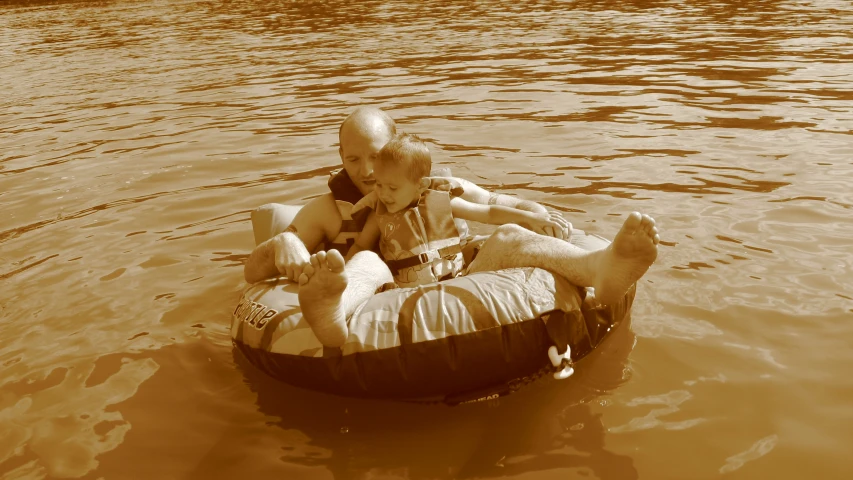 an old man and a toddler ride on an inflatable tube