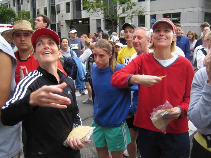 the people are standing in the middle of the street and some have sandwiches