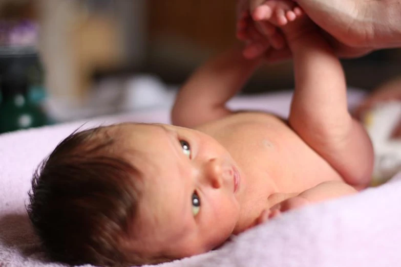 a baby laying on a bed in a crib looking up