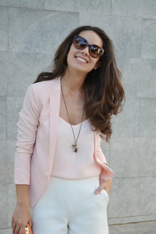 a woman wearing glasses smiles as she holds a handbag