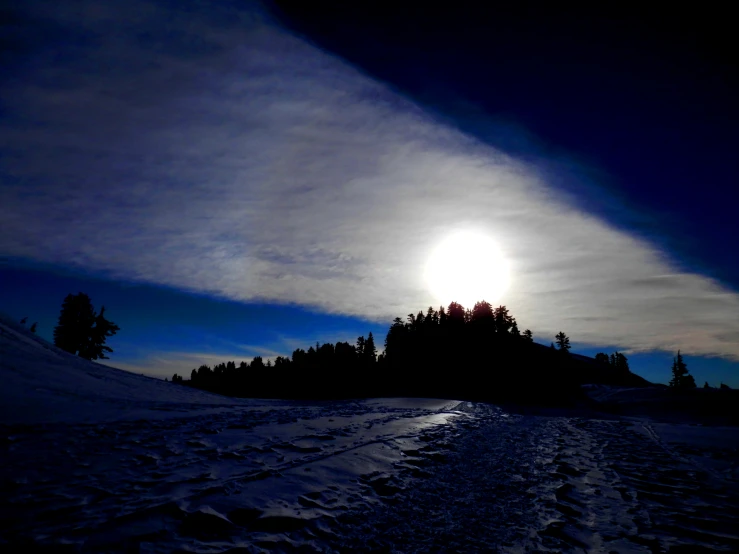 the sun is setting behind some small snow capped hill