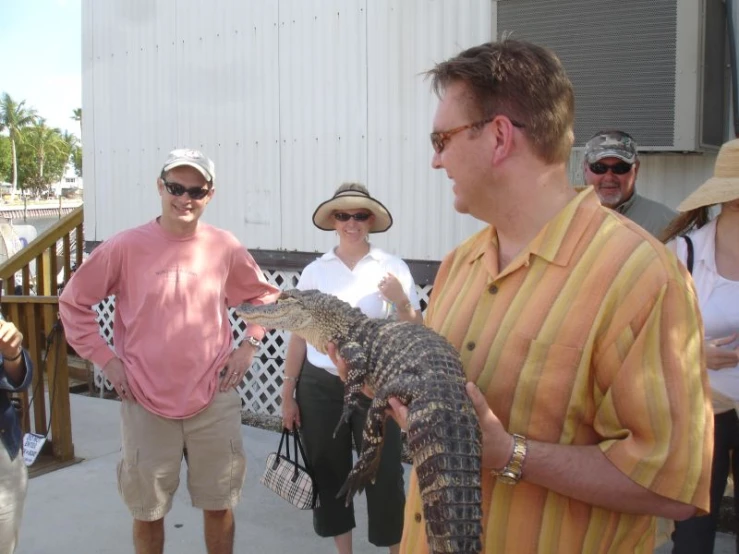 several men are standing and holding small alligator