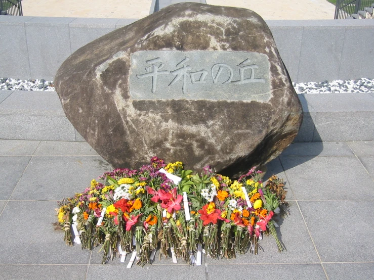 a large stone with flowers and words written in it