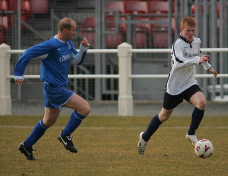 two young men playing soccer on a field