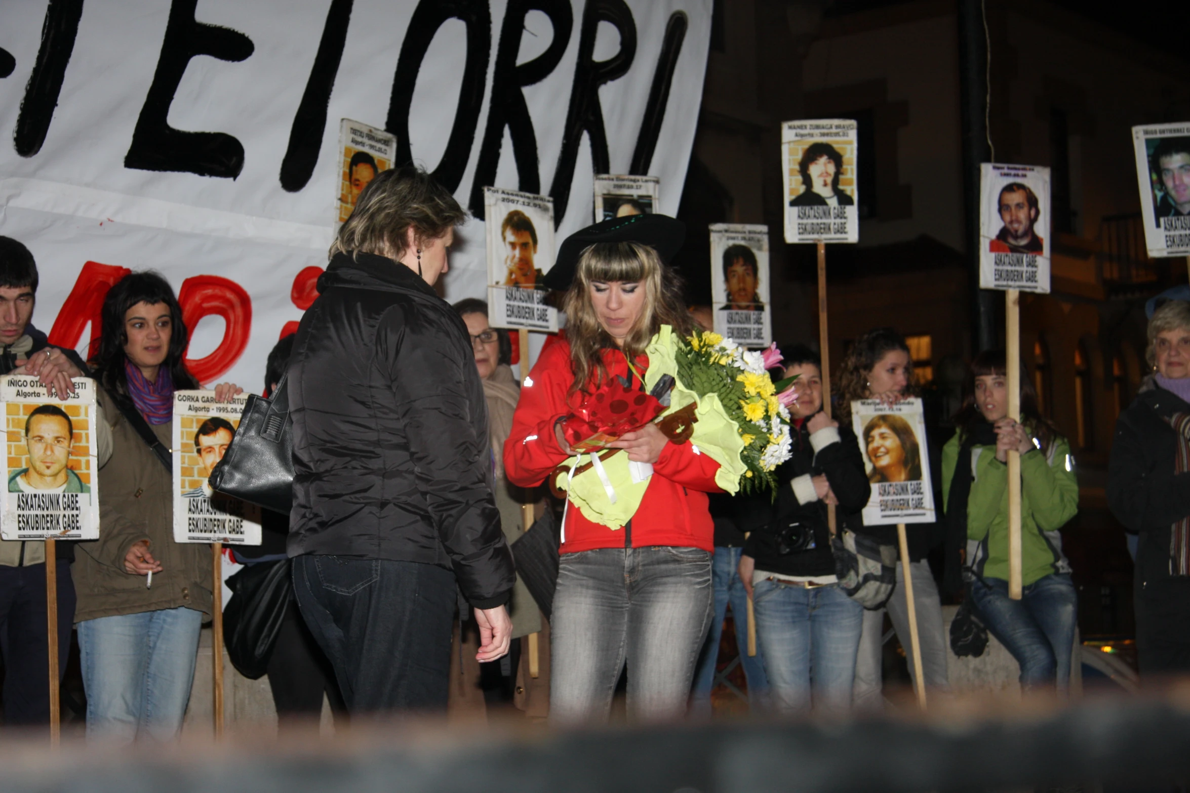 a crowd of people stand holding up posters and placards