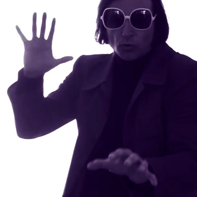 a man wearing sunglasses is pointing at his hand