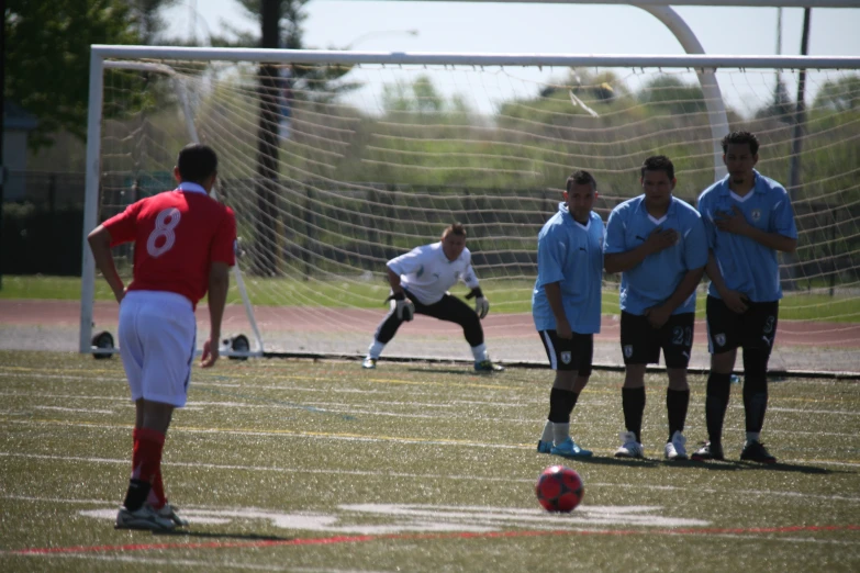 the soccer players are waiting on the field for the ball to come towards their goal