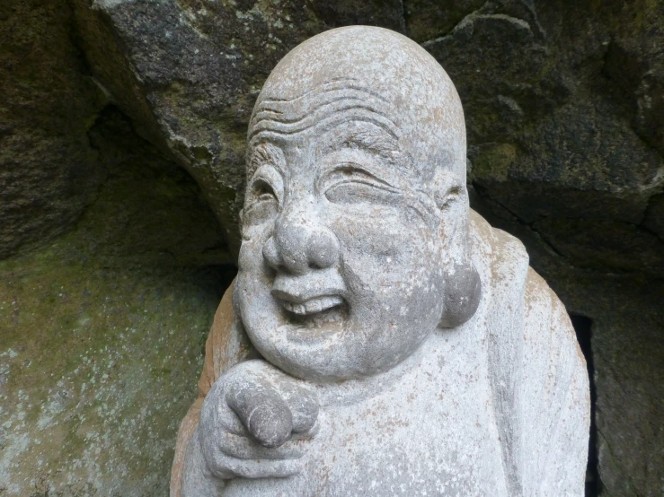an old statue with a face sitting between two rock formations