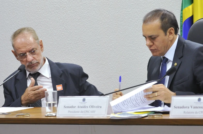 two people sitting at a table with paperwork