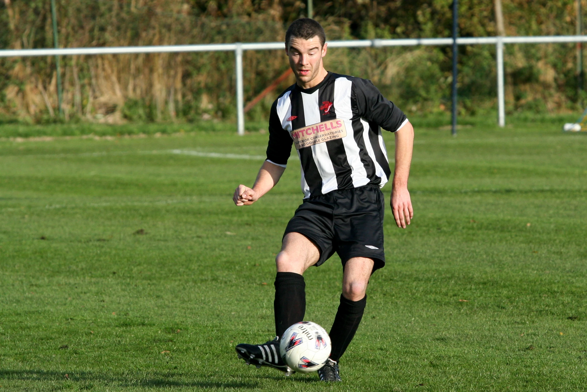 a man in black and white soccer uniform kicking the ball