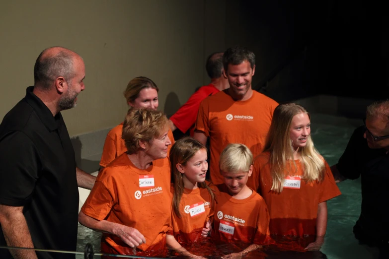 a group of people wearing orange shirts next to water