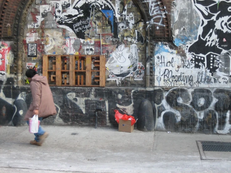 a woman walking in front of some graffiti