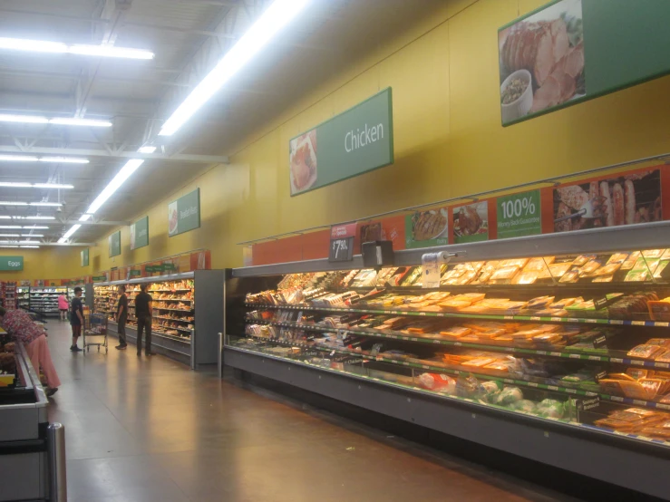 several people looking at a food display in the middle of a store