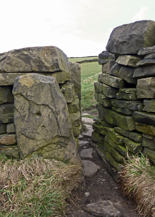 stone walls and walkway leading to a field with grass