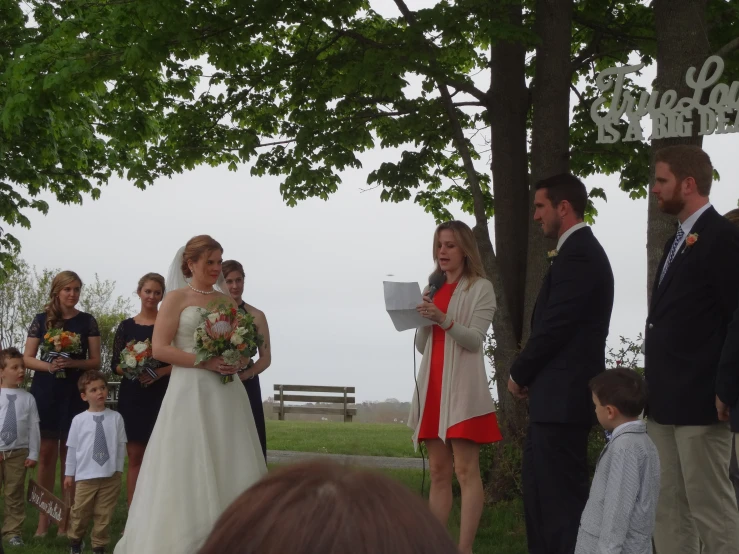 a bride and groom under a tree while an aisle begins