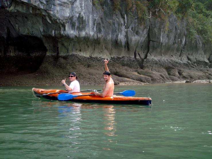 a man and a woman on kayaks waving towards the camera