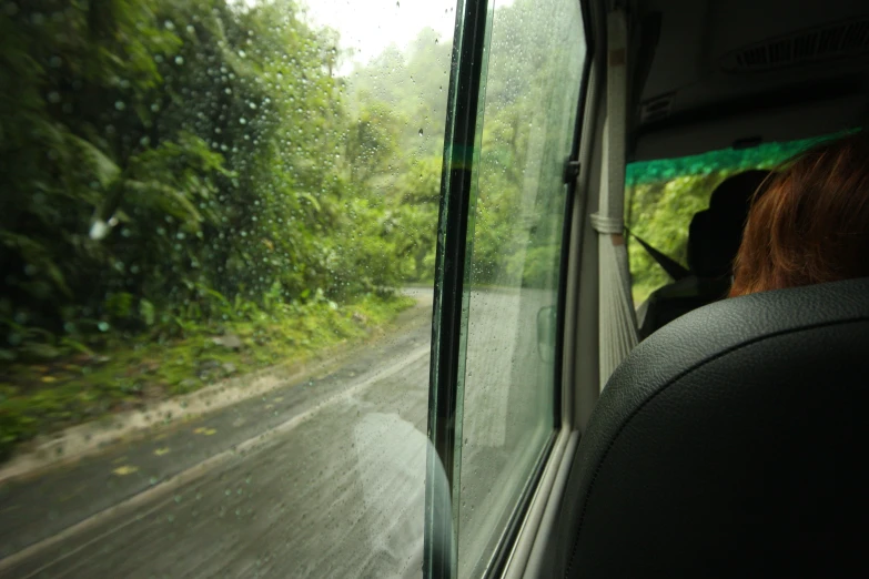 the windshield of a van on a wet road with a person driving