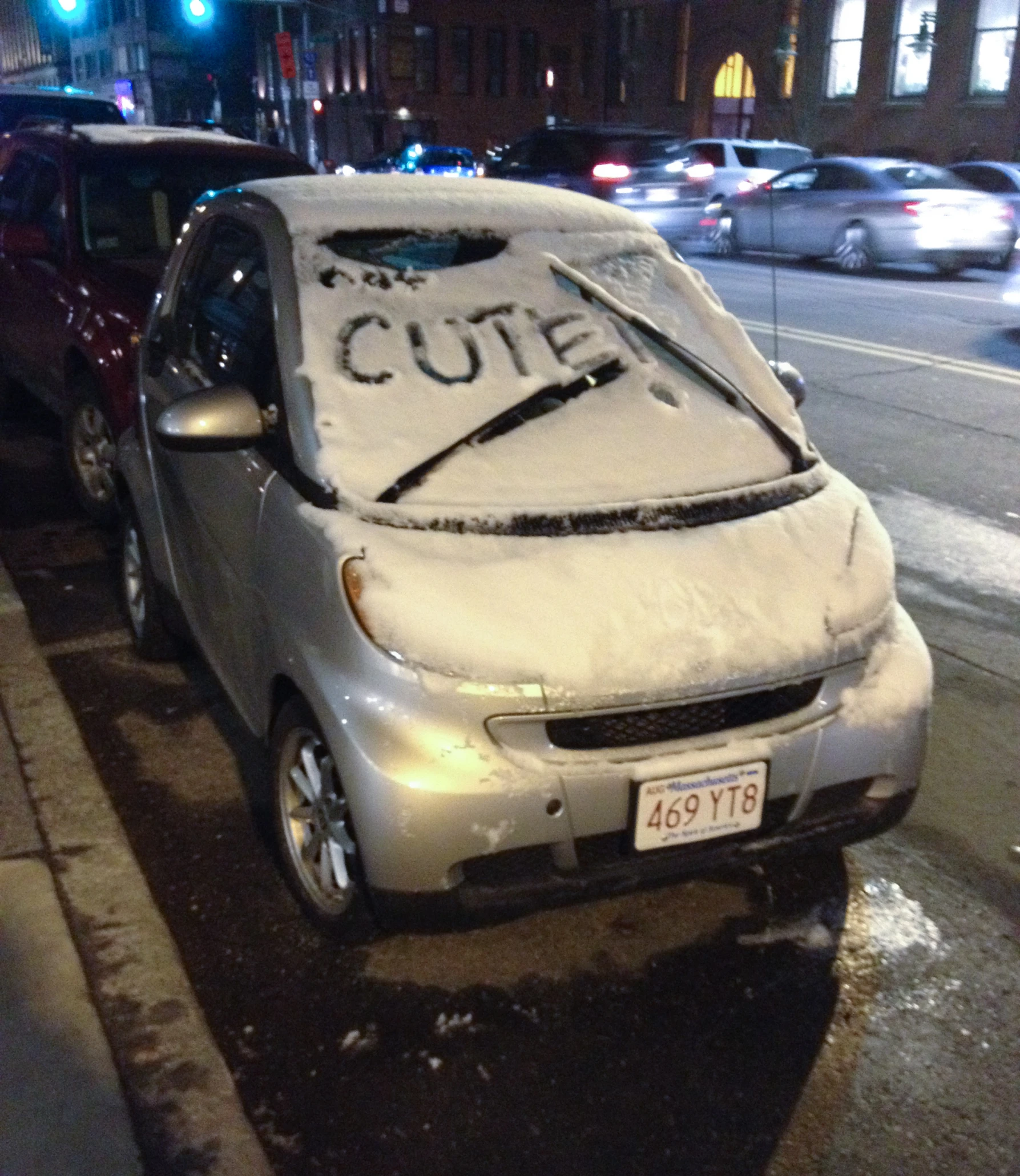 cars on the side of a busy street covered in snow