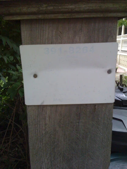 the sign has three nails on it next to the wooden fence