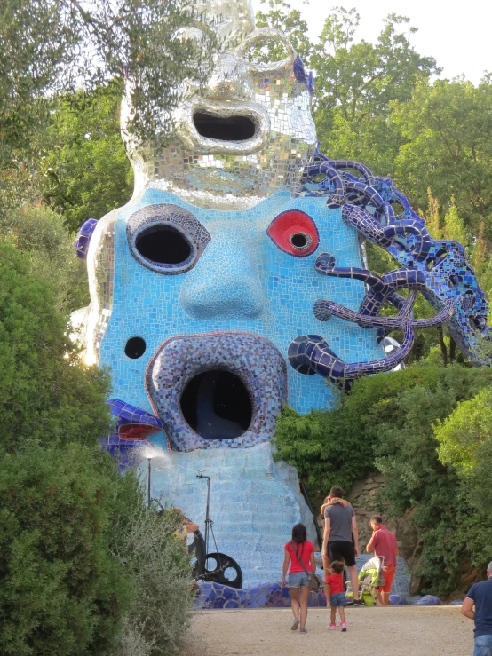 a giant head of a blue creature with two children standing in front of it