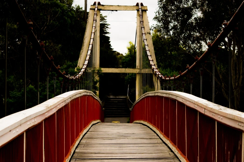 a small wooden bridge with ropes and railing
