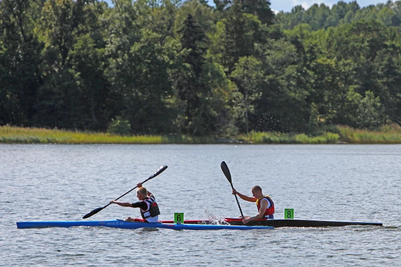 two people in canoes paddling across a lake