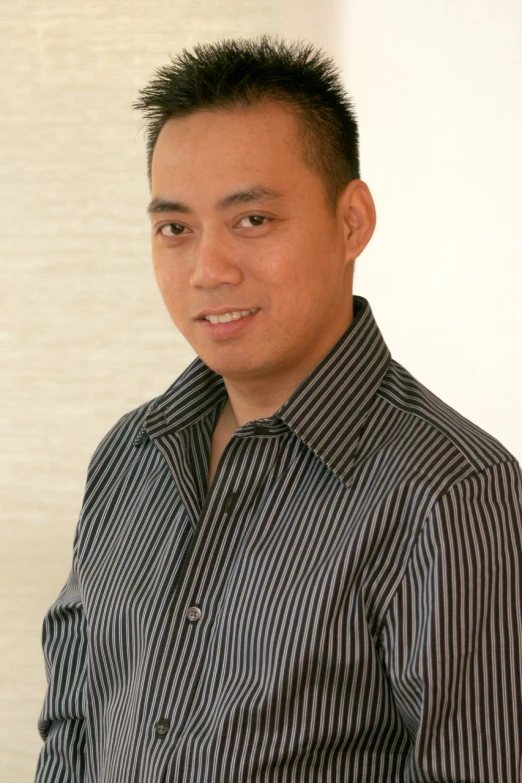 an asian man standing wearing a striped shirt