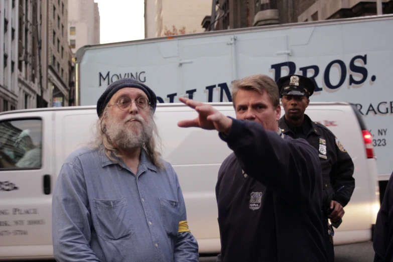 two men with a man pointing out soing on the street