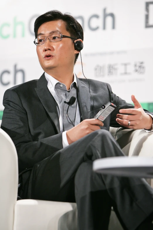 an asian man wearing headphones speaking at a conference