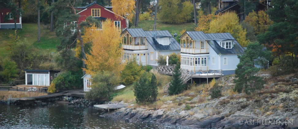 three white homes sit on the shore in autumn