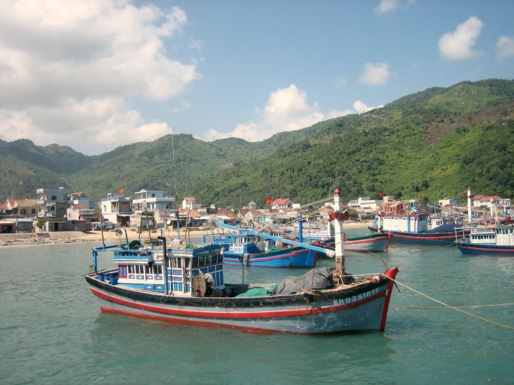 many boats docked in the water near a large mountain