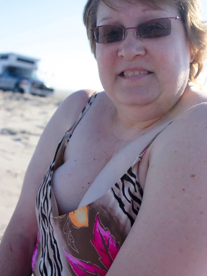 a woman in sunglasses posing for the camera on the beach