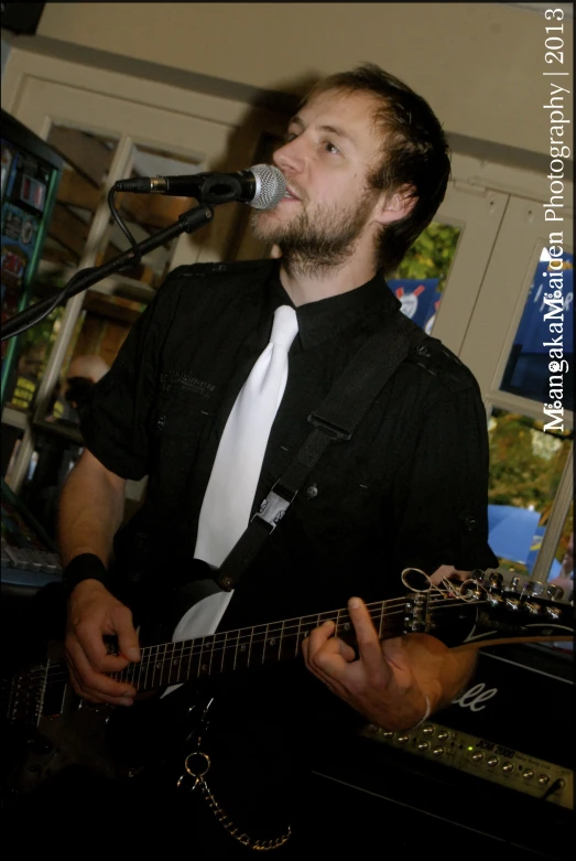 man playing guitar with microphone near him in room