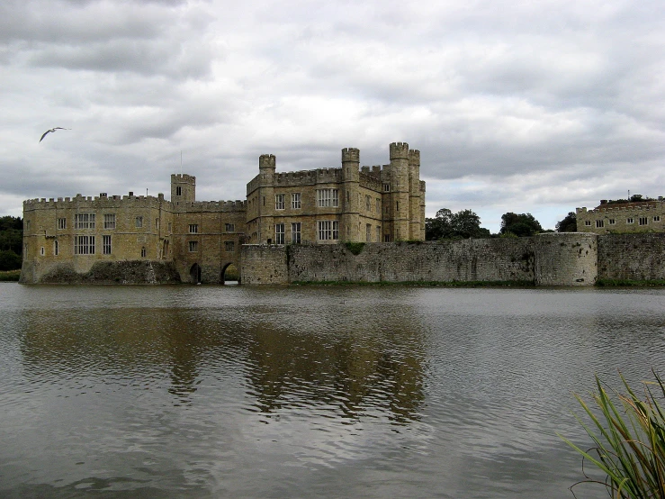 a large castle sits above the water on a cloudy day