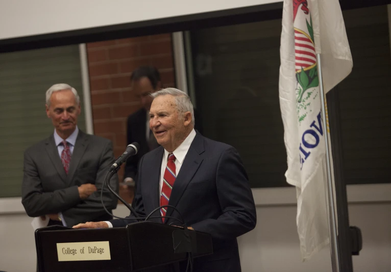 three men standing behind microphones talking into microphones