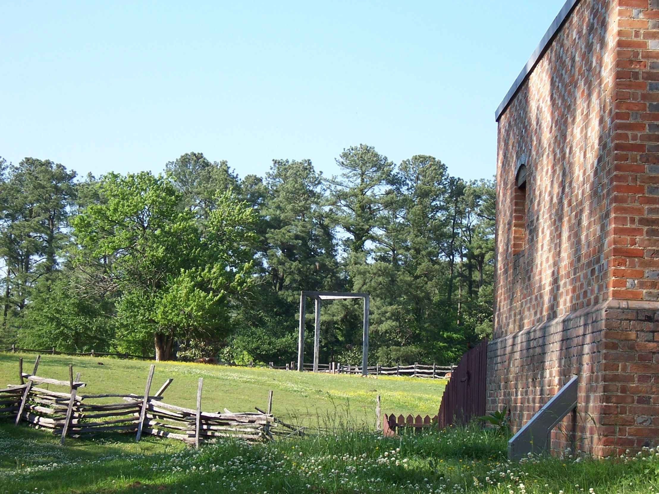 a field filled with green grass next to a tall brick building