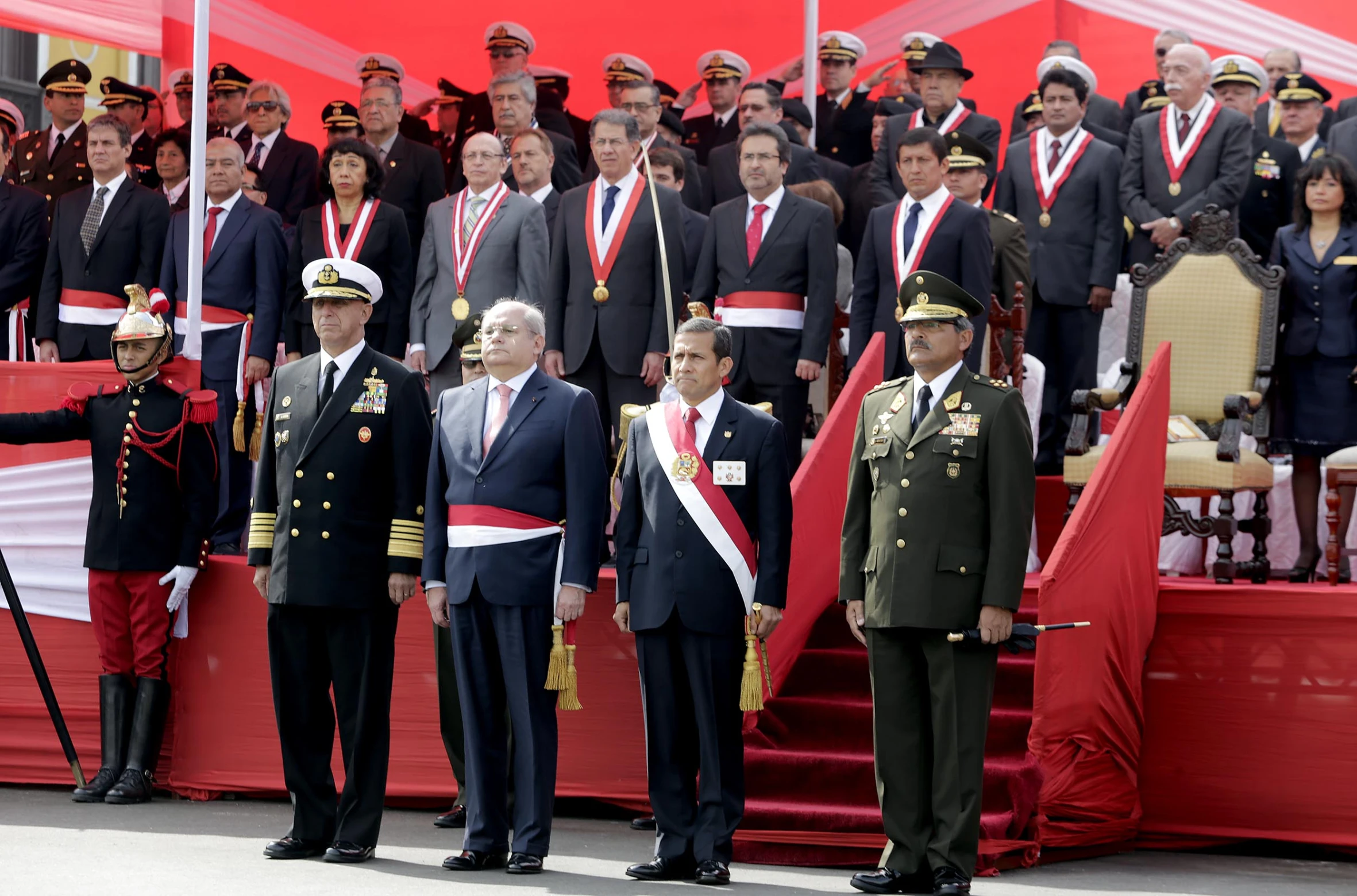 a man with a medal stands at a ceremony, accompanied by a group of people