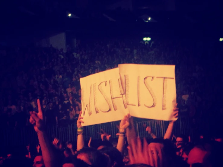 a crowd at a concert holding up a protest sign