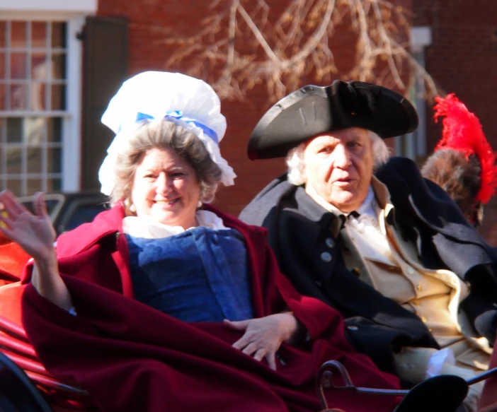 two people dressed in fancy clothing riding a carriage