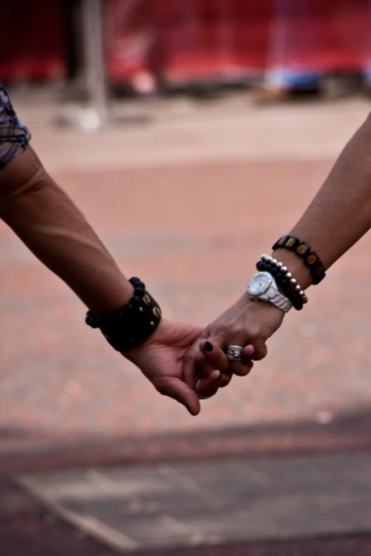 two people holding hands while walking down the street