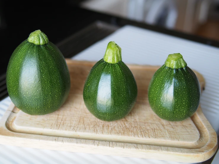 three large green fruit are next to each other on a  board