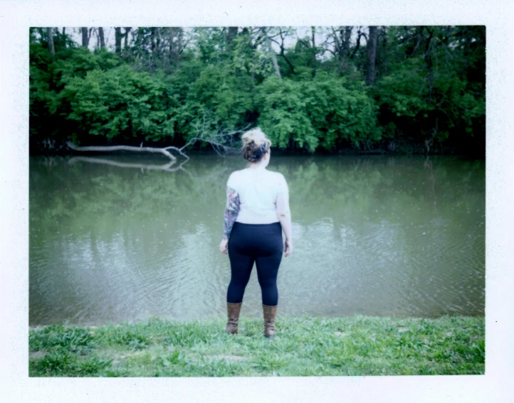 an old woman stands looking out over the water