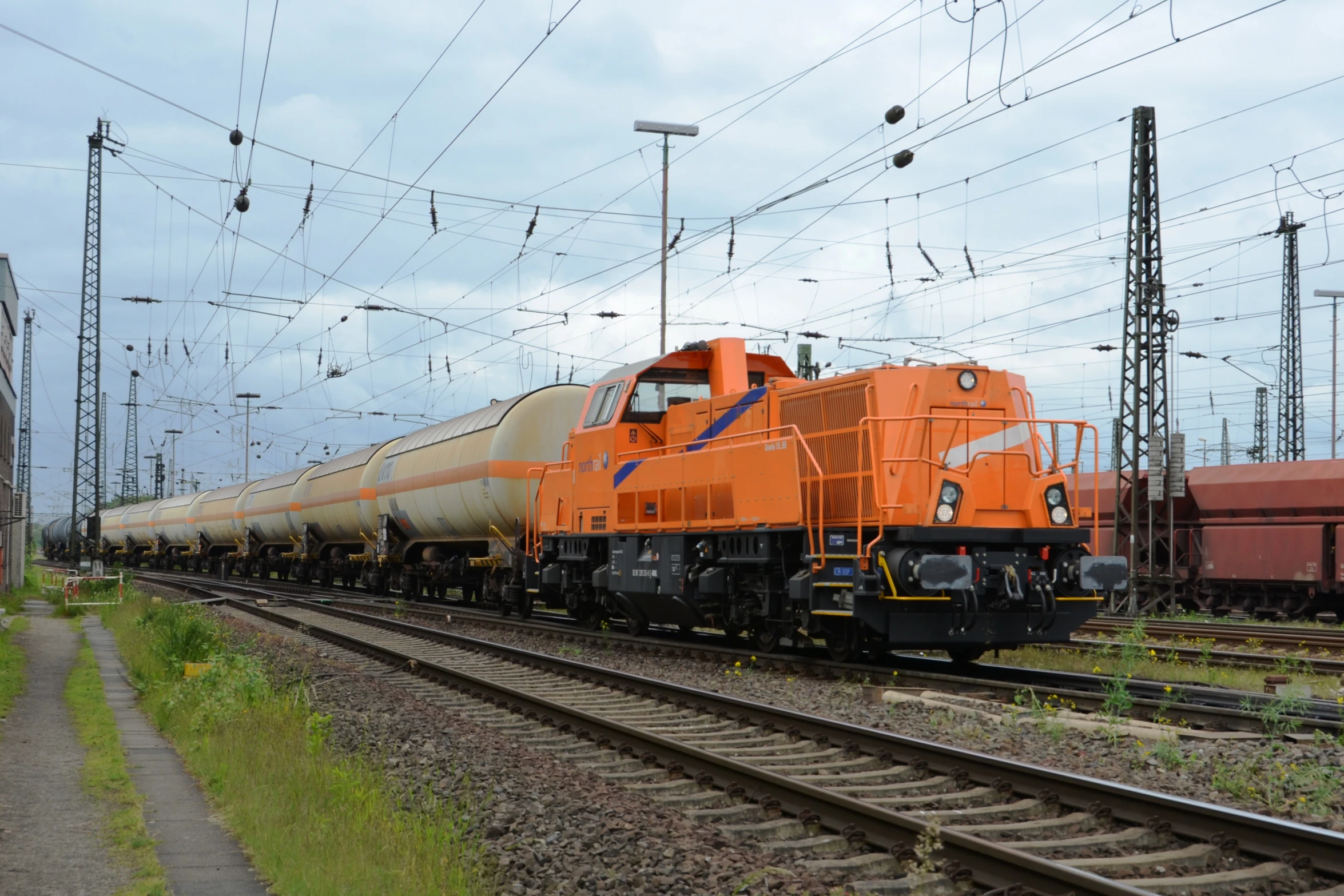 orange freight train on tracks with power lines above