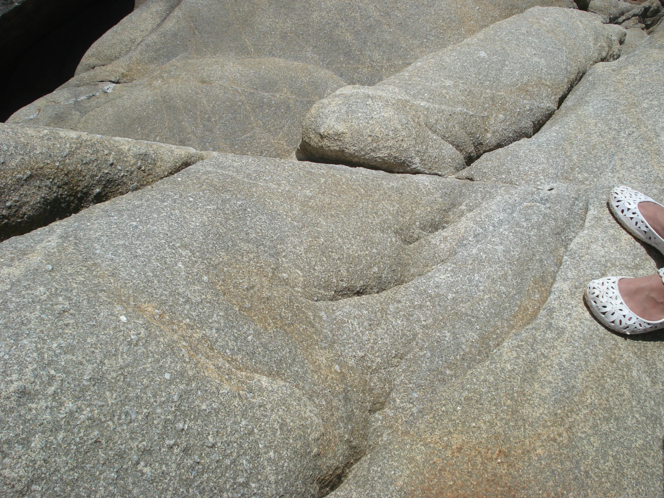 a person's shoes on the rocks by some water