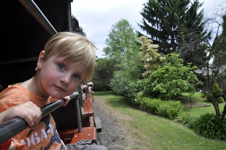 a boy riding on a small train in the middle of grass