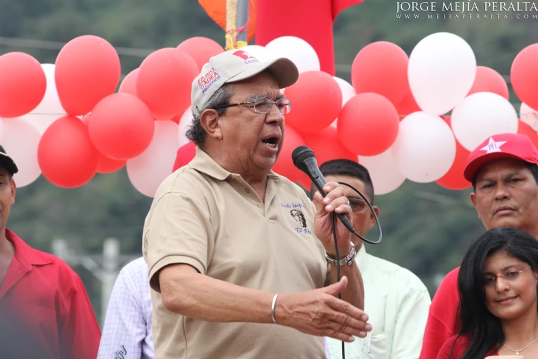 the man speaks at an outdoor function with people watching