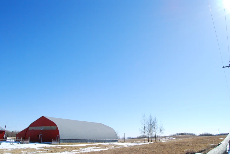 a large red barn sits in a field of snow