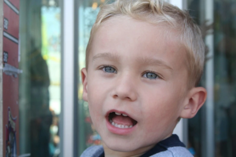 a boy with blue eyes is wearing a gray jacket